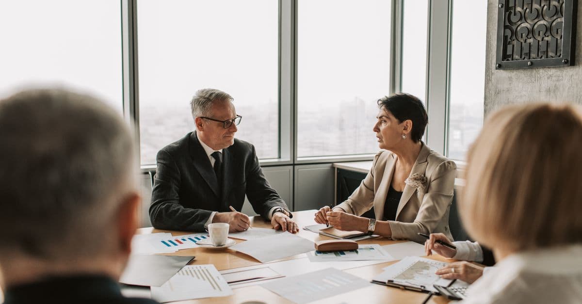 A group of professionals discussing documents in a boardroom meeting