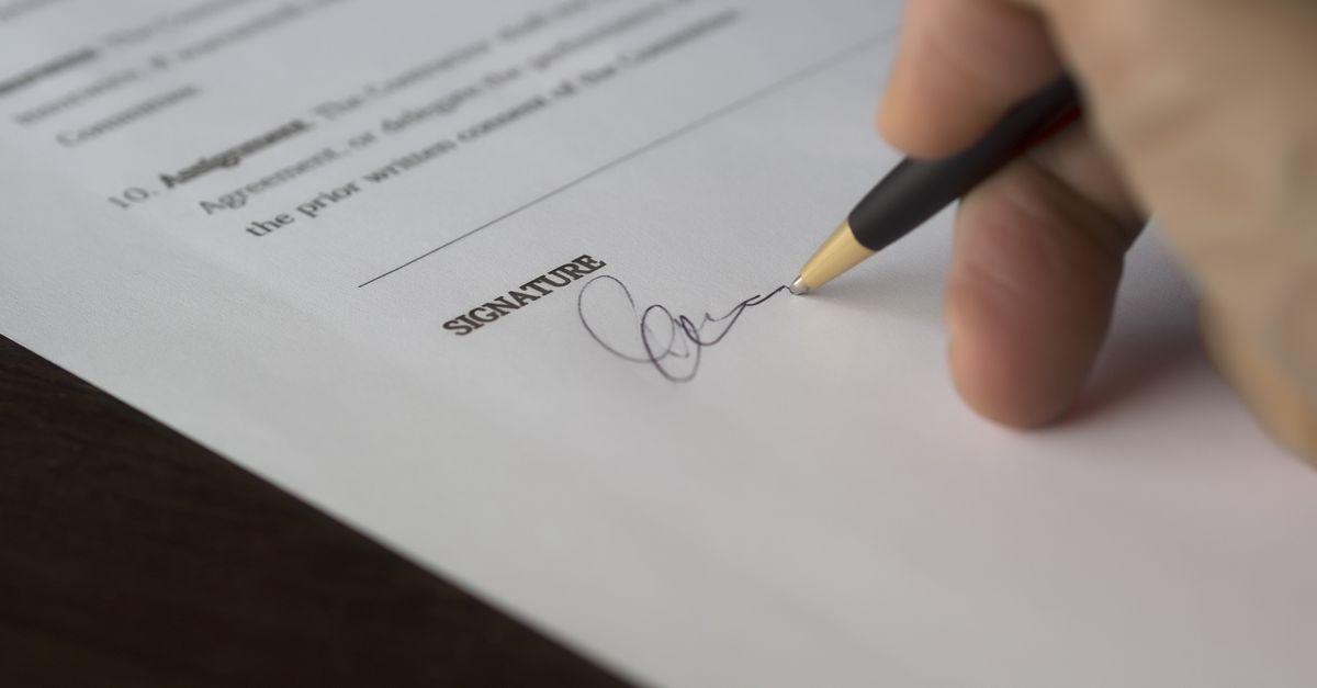 A hand signing a formal contract with a pen